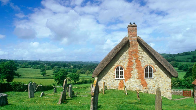 Loughwood Meeting House from outside on a sunny day with peaked roof and graveyard